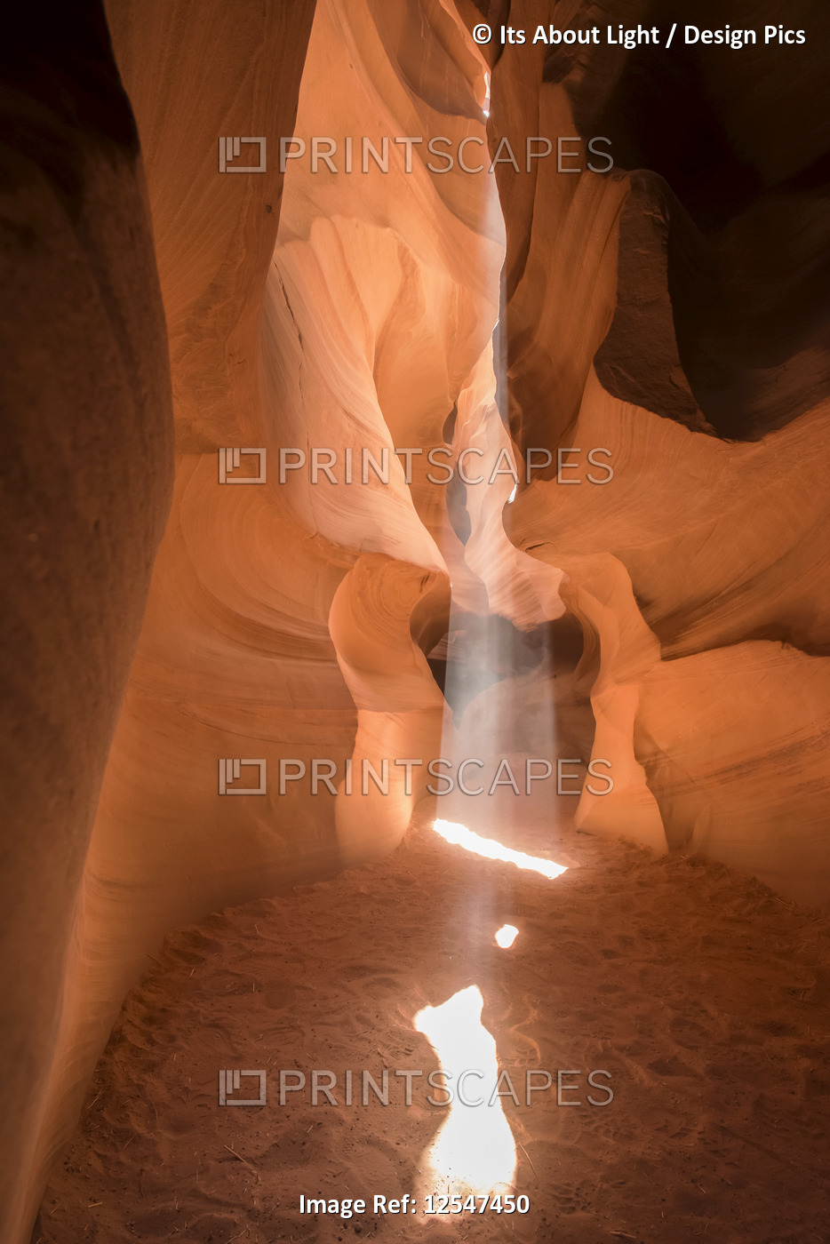 Sunlight streams through a natural hole in the sandstone to the sand below, ...